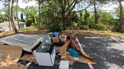 Household furniture and appliances staged in a parking lot for pickup