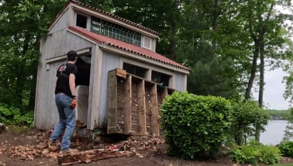 Worker dismantling an old wooden shed near a lake
