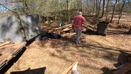 Worker collecting yard waste and debris in a wooded lot